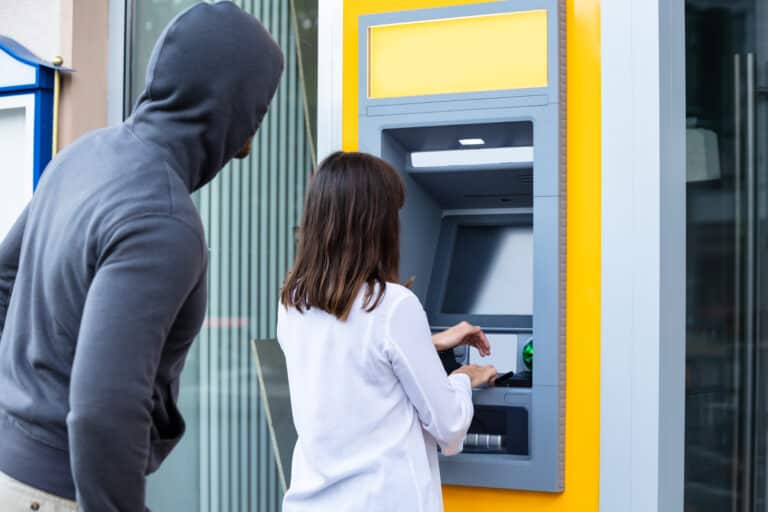 Thief Looking At Woman Entering The Pin In Atm