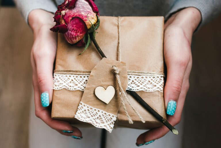 Woman Holding Wrapped Gift With Rose Brown Wrapper